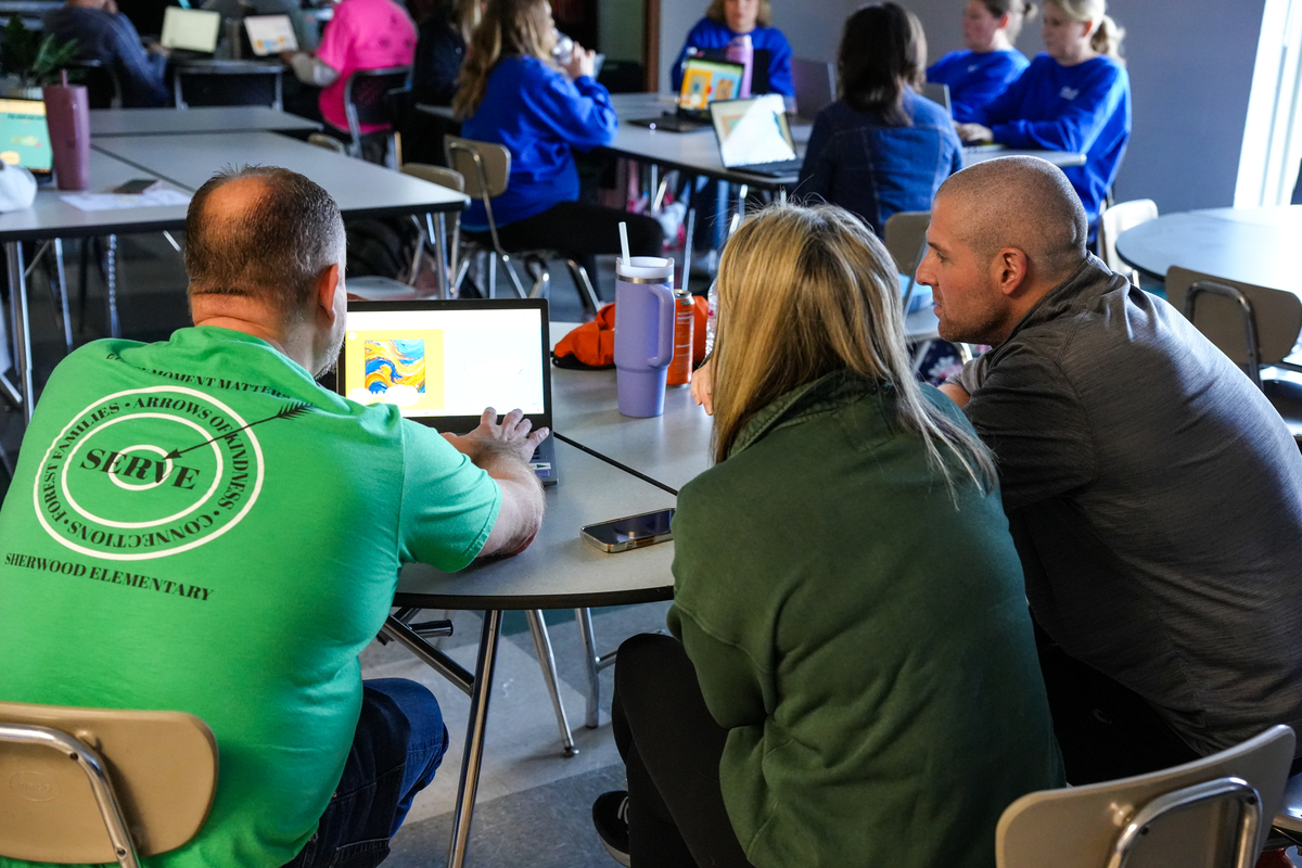 Three staff members look at training information on a laptop
